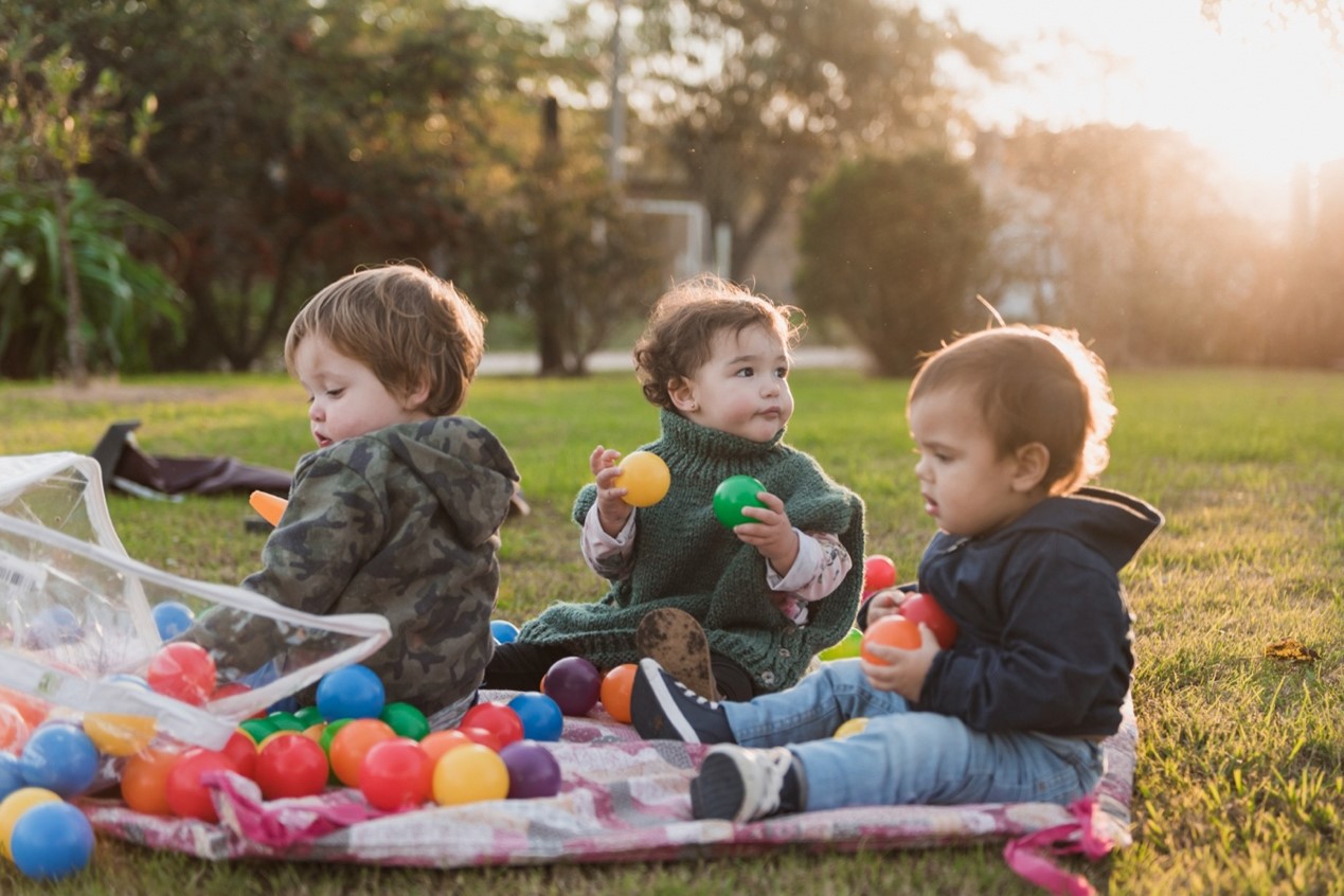 Children playing in a cozy backyard in a home-based childcare Auckland, surrounded by toys and natural outdoor scenery